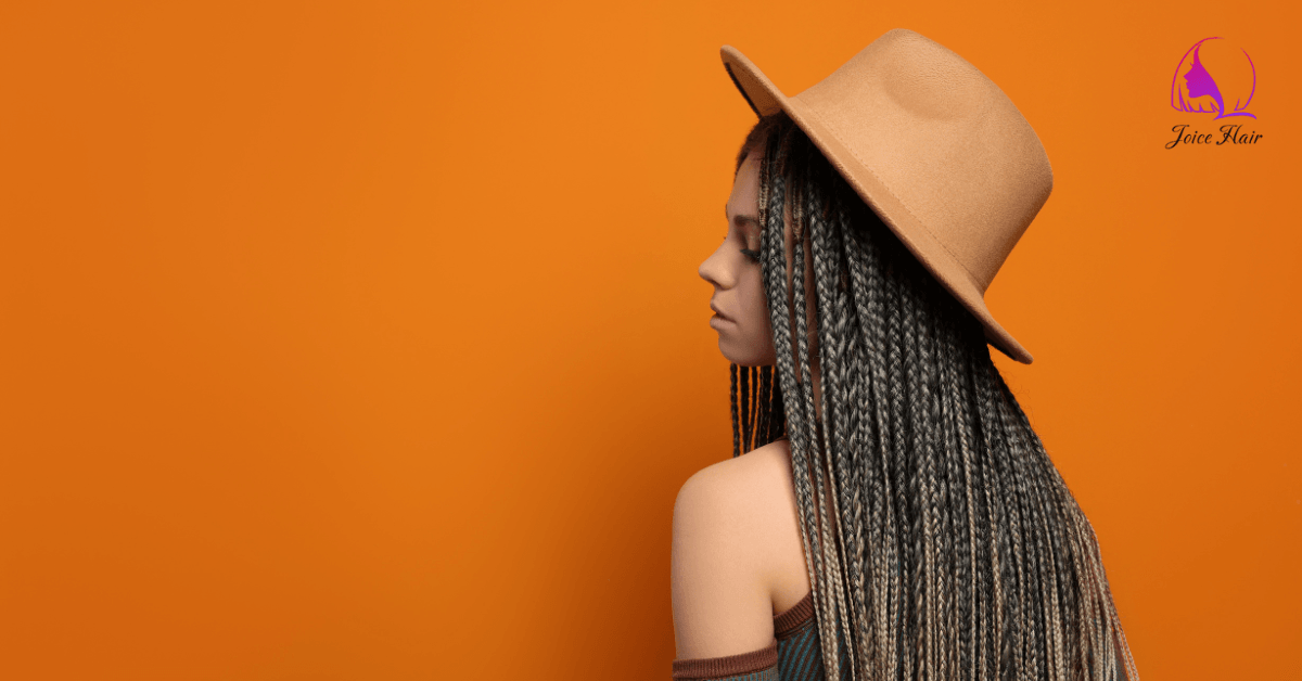 Woman with long braids created using bulk hair for braiding, wearing a hat against an orange background.